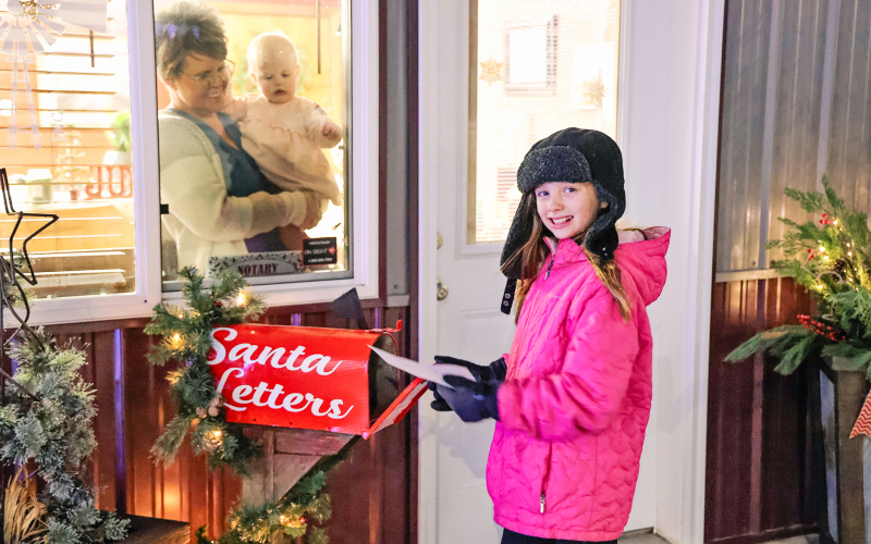 Mary Tanke drops her letter to Santa into the magic mailbox at Jerauld County Title Company as owner Michelle Tong and granddaughter Hallie Anson look on.
