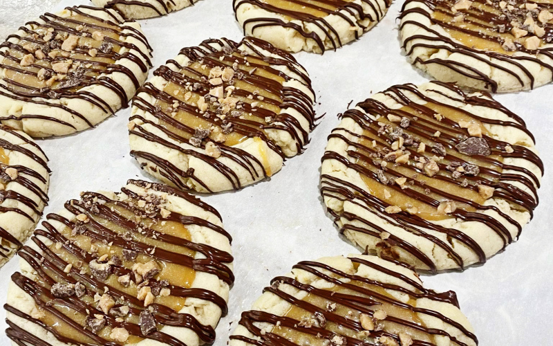 A close-up of Emma Haeder’s popular Twix cookie from Miss Rosalie’s Sweets and Treats highlights the rich layers of chocolate, caramel and shortbread that have made the flavor a customer favorite.