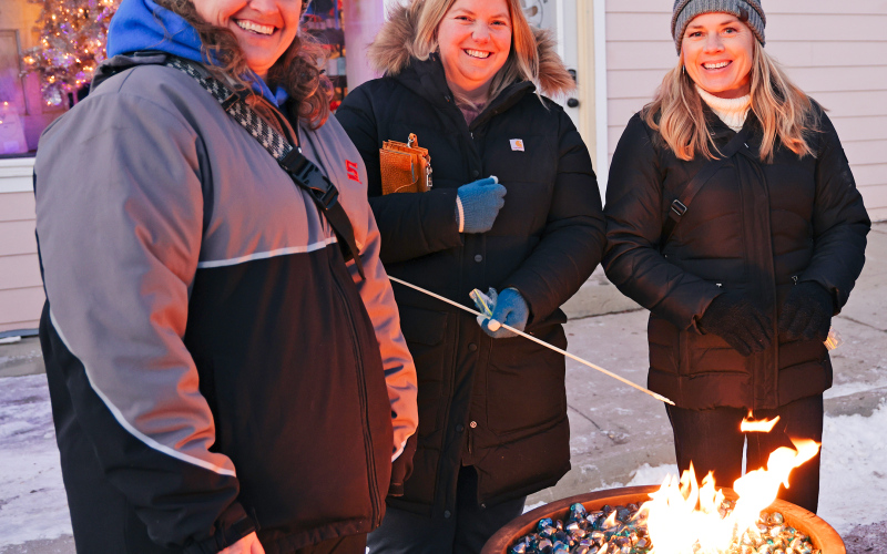 Ann Scheel, Kristina Karsky and Shannon Fagerhaug warm up beside a fire pit.