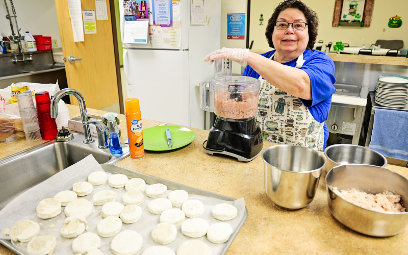 Marla Ness prepares food at the Wessington Springs Senior Community Center, where reduced services and funding challenges have impacted both meal offerings and staff hours. (KRISTI HINE / TRUE DAKOTAN)