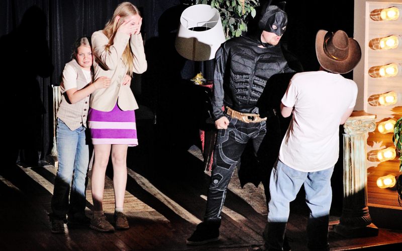 Lily Roesler (playing Nancy Drew) peeks through her hands as Paisley Kapp (as Joe Hardy) clutches her in fear as they witness an altercation between Holden Jackson (playing Batman) and Frank Hardy (as played by Zandon Beyer).
