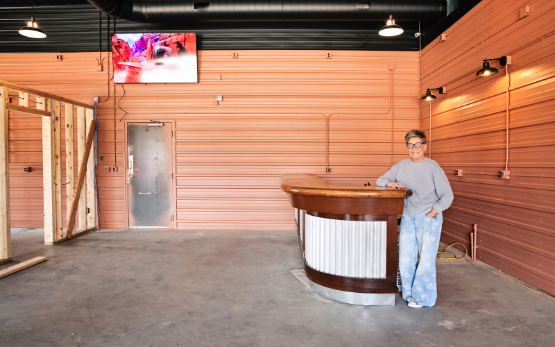Lori Danburg, manager of the Farmers Union Oil gas station and convenience store in Wessington, stands inside the future County Line Bar and Bites, leaning against the repurposed vintage bar brought in from a former establishment in Parkston.