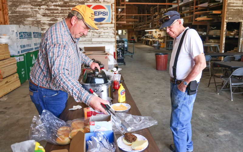 Farmland Building Supply Board Member Dean Duxbury serves a burger to Mike Hazzard during the company’s annual Customer Appreciation Day on June 3 in Wessington. The event featured burgers, beans, chips, cookies and refreshments as a thank-you to customers for their continued support. (KRISTI HINE / TRUE DAKOTAN)