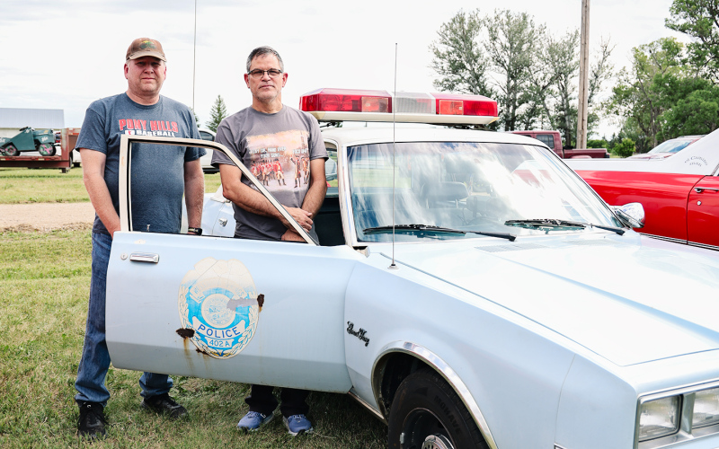John McWilliams, right, of Fort Worth, Texas, and Jason Wenzel of Wessington Springs stand beside the fully restored 1985 Plymouth Gran Fury that once served as the Springs Police Department patrol car driven by Jason's father, longtime Police Chief Larry 'Hawkeye' Wenzel. McWilliams brought the cruiser to the Leap to Lane Car Show, where it sparked memories and stories from residents. (KRISTI HINE / TRUE DAKOTAN)