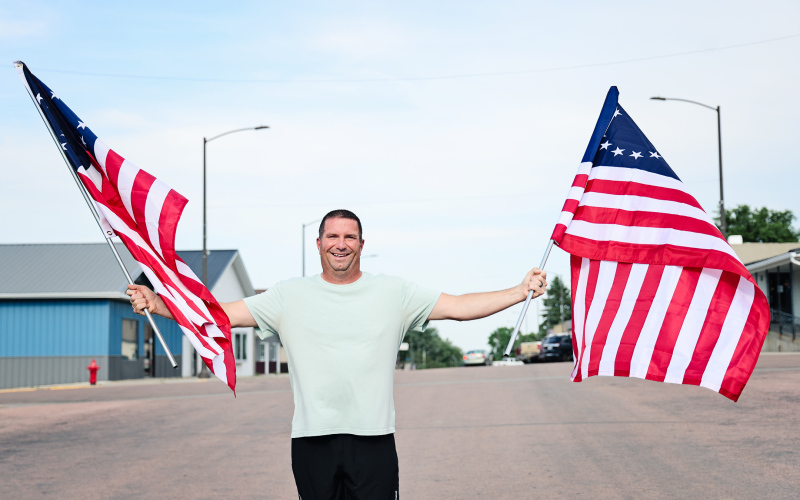 Marcus Damm stands on Main Street in Wessington Springs holding two of the 24 Betsy Ross-style American flags he purchased and installed along downtown light poles ahead of the Fourth of July holiday. Inspired by a conversation with his wife, Lynn, he organized the patriotic display, creating a festive welcome for residents and visitors during the holiday weekend.