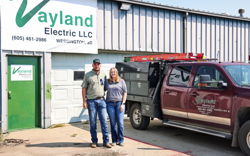 Logan and Josie Schiltz stand outside the Vayland Electric shop near Wessington, where Logan launched his electrical contracting business in January. The shop once housed his grandfather’s Schiltz Manufacturing operation, adding a new chapter to the family property’s entrepreneurial history. (KRISTI HINE / TRUE DAKOTAN)