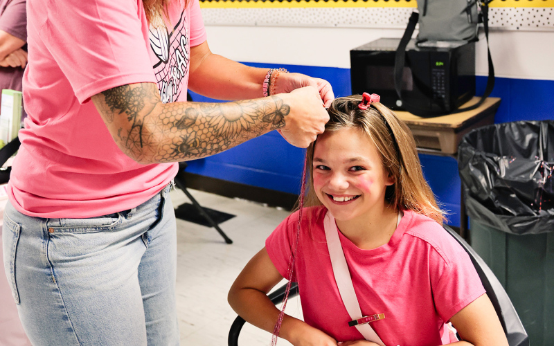 Barbie Reed adds hair tinsel to Carlayna Waters’ hair as part of another fundraiser.