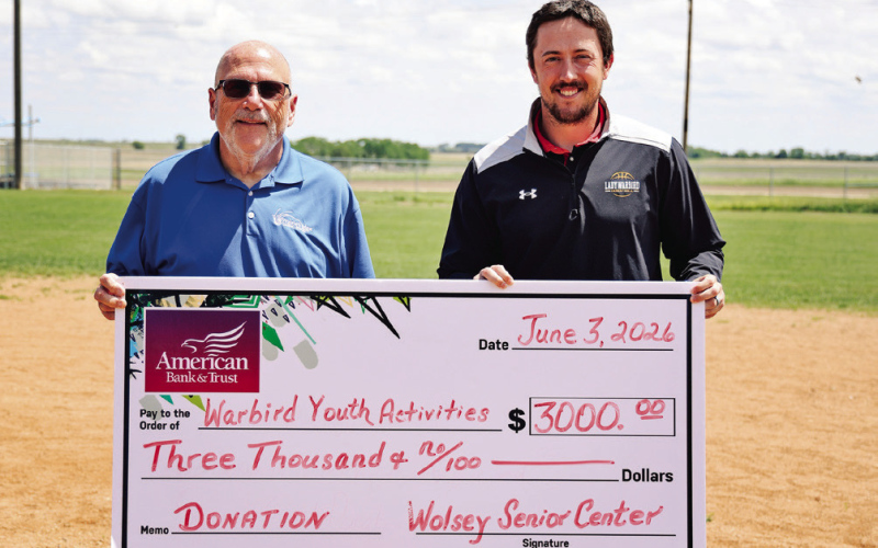 Wolsey Senior Center board member Dave Burnison, left, presents a $3,000 donation to Riley Donovan to support the Wolsey Summer Recreation baseball program. The contribution helped expand the program to include both tee ball for ages 4-5 and coach-pitch baseball for ages 6-7. Nearly 40 youth are participating this summer, with games scheduled Mondays and Wednesdays throughout June. (KRISTI HINE / TRUE DAKOTAN)