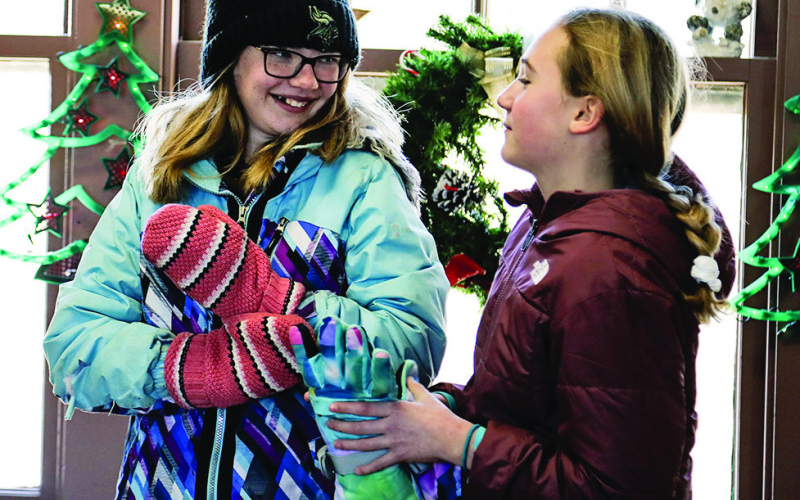 Winter Park “regulars” Madilyn Gaikowski and Taryn Bartel don their mittens in the Field House before catching a wagon ride through the park earlier this month.