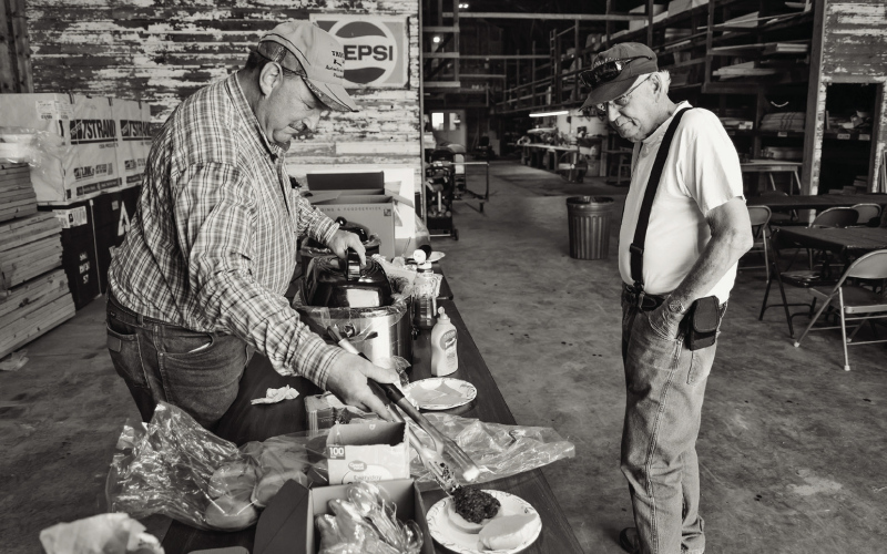 Farmland Building Supply Board Member Dean Duxbury serves a burger to Mike Hazzard during the company’s annual Customer Appreciation Day on June 3 in Wessington. The event featured burgers, beans, chips, cookies and refreshments as a thank-you to customers for their continued support. (KRISTI HINE / TRUE DAKOTAN)