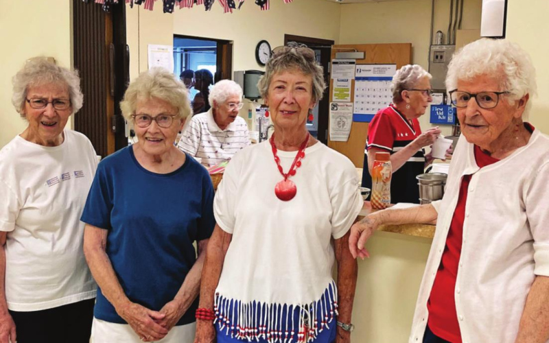 Luella Teveldal, Lenora Pawlowski, Alice Willman and Marilyn Robbins with Mary Lou Cameron and Marlys Schryock in the kitchen take a break from serving customers at the senior center ice cream social held post-parade.