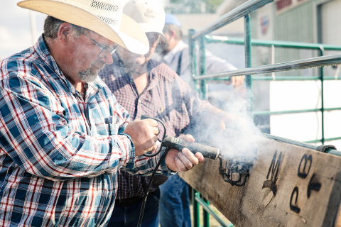 Pat Fastnacht burns a board with his brand, as his dad Jerry looks on. 