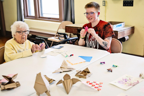 Faith Easter leads an origami class. Class attendee Peg Olson is pictured at left.