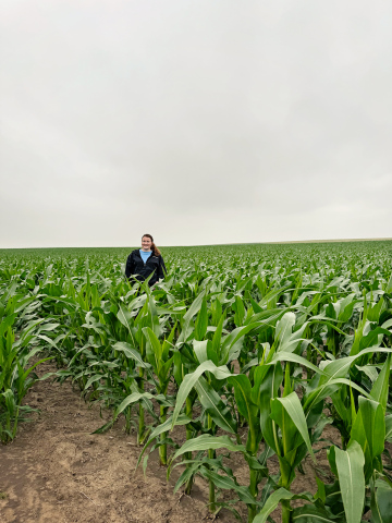 Riley Roduner stands in a corn field on her family’s farm and ranch, located three miles west of the Jerauld / Buffalo County line. Her dad Steve said that the field pictured was planted on the 8th of May. Roduner said that while this field would normally yield 120-140 bushels, this year has the potential to yield 180-190 bushels if favorable conditions continue during the growing season. PHOTO BY REMIE RODUNER FOR THE TRUE DAKOTAN