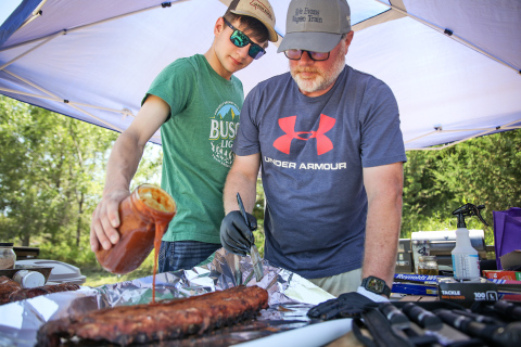 Father-son team Chris and Austin Schimke work together to apply homemade barbecue sauce.