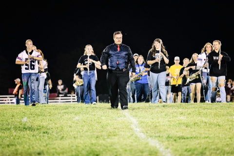 Band instructor Andrew McCormick leads the marching band onto the field last Friday night during halftime.