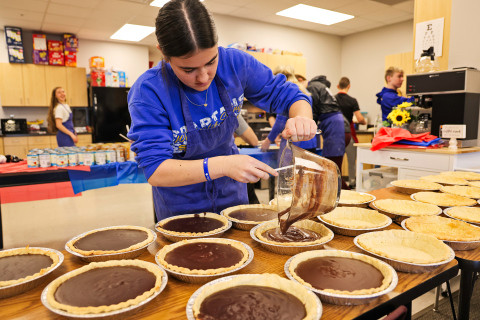 As area families sit down to enjoy their Thanksgiving meal together this Thursday, chances are they’ll be savoring a pie made by Wessington Springs High School (WSHS) students, as part of a longstanding local tradition. Pictured hard at work Tuesday during the annual service-oriented pie baking project, Remie Roduner spoons chocolate filling into pie crusts. KRISTI HINE / TRUE DAKOTAN 