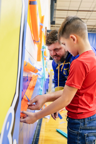 During the educational event aimed at fostering family engagement in learning, Cody Hasty and son Miles work on the “marble wall.”
