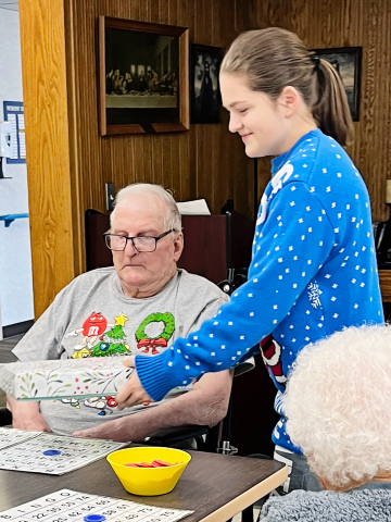 WSHS student Kennedy Kolousek delivers a gift to Weskota Manor Avera resident Les Caffee as part of her angel tree senior project. PHOTO COURTESY LIZA KOLOUSEK
