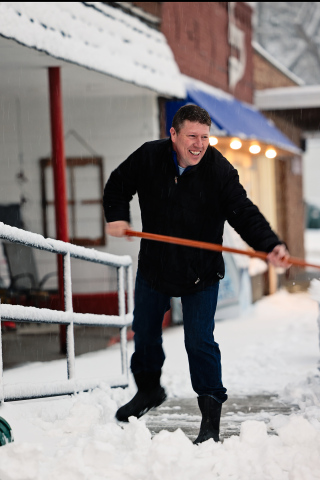 Springs Food Market owner Ryan Jensen scoops the sidewalk on Main Street Tuesday morning. 
