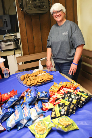 Linda Willman, Teresa and Craig Fonder dish up pulled pork sandwiches accompanied by chips and cookies, served up by Melanie Schelske.