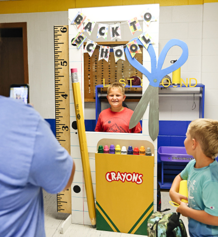 Chelsea Cashman snaps a cell phone photo of son Hayes as his brother Harvey looks on during Back-to-School Night. 
