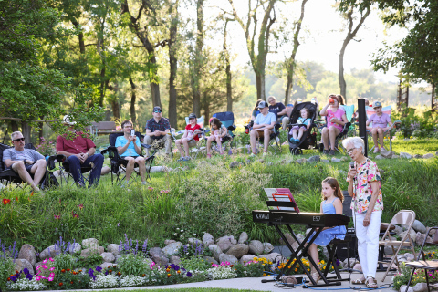 Lois Feistner introduces one of the performers, Emmie Bartel during the July 24, 2025 Music in the Garden. 