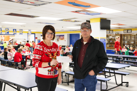 Wessington Springs resident Larry Powell presents a check for more than $3,500 to Wessington Springs Elementary School Principal Becky Fjerstad in the WSES lunchroom. The funds were raised through Christmas train rides during the town-wide holiday kickoff on Dec. 1. Proceeds from the rides were donated to the Wessington Springs School District lunch program to help cover the cost of additional servings for students. (KRISTI HINE / TRUE DAKOTAN)