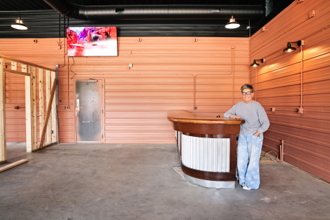 Lori Danburg, manager of the Farmers Union Oil gas station and convenience store in Wessington, stands inside the future County Line Bar and Bites, leaning against the repurposed vintage bar brought in from a former establishment in Parkston.