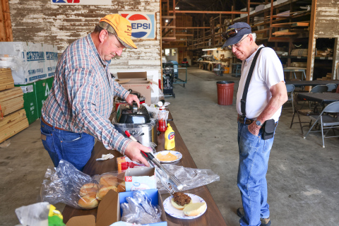 Farmland Building Supply Board Member Dean Duxbury serves a burger to Mike Hazzard during the company’s annual Customer Appreciation Day on June 3 in Wessington. The event featured burgers, beans, chips, cookies and refreshments as a thank-you to customers for their continued support. (KRISTI HINE / TRUE DAKOTAN)