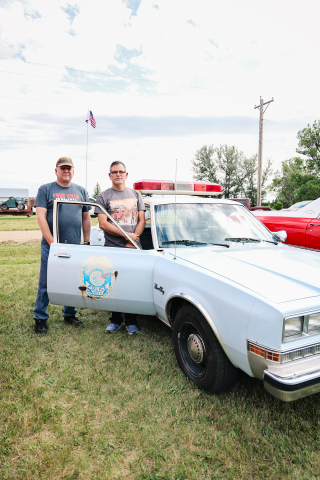 John McWilliams, right, of Fort Worth, Texas, and Jason Wenzel of Wessington Springs stand beside the fully restored 1985 Plymouth Gran Fury that once served as the Springs Police Department patrol car driven by Jason's father, longtime Police Chief Larry 'Hawkeye' Wenzel. McWilliams brought the cruiser to the Leap to Lane Car Show, where it sparked memories and stories from residents. (KRISTI HINE / TRUE DAKOTAN)