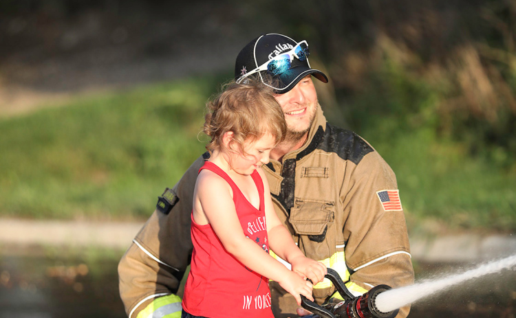 Fire Chief Jim Vavra helps Bristol Grohs during the friendly water barrel fight with fireman Cody Barber (not pictured).