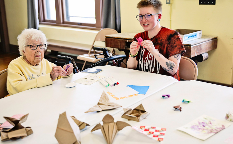 Faith Easter leads an origami class. Class attendee Peg Olson is pictured at left.