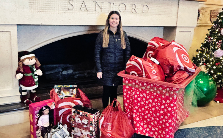 Wessington Springs High School senior Jada Kolousek poses with a pile of gifts donated to Sanford Children’s Hospital in Sioux Falls, a project inspired by her late classmate Estrellita Cardona. (COURTESY PHOTO)