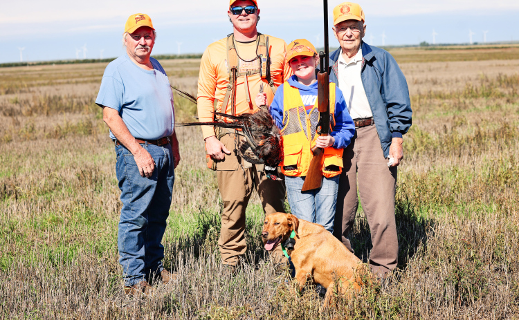 Four generations of hunting tradition come together following the Oct. 3 Pheasants Forever Youth Hunt. From left, Steve Winter, Jason Weber, Hadley Weber and Dayle Winter stand in the field with Hadley’s first pheasant. Hunting dog Minnie joins the group in front.