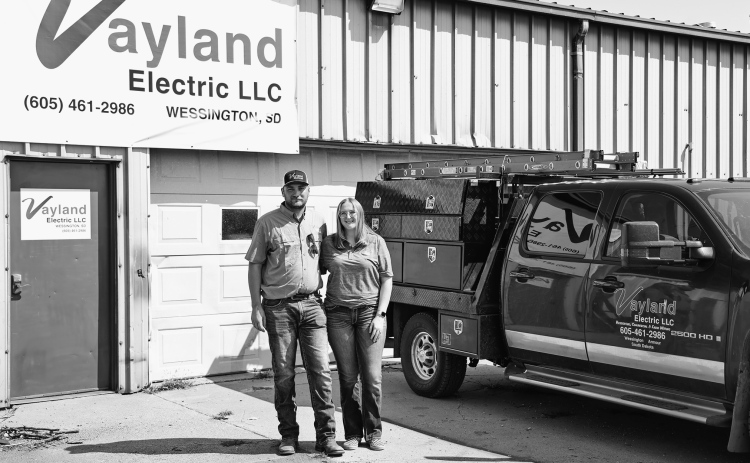 Logan and Josie Schiltz stand outside the Vayland Electric shop near Wessington, where Logan launched his electrical contracting business in January. The shop once housed his grandfather’s Schiltz Manufacturing operation, adding a new chapter to the family property’s entrepreneurial history. (KRISTI HINE / TRUE DAKOTAN)